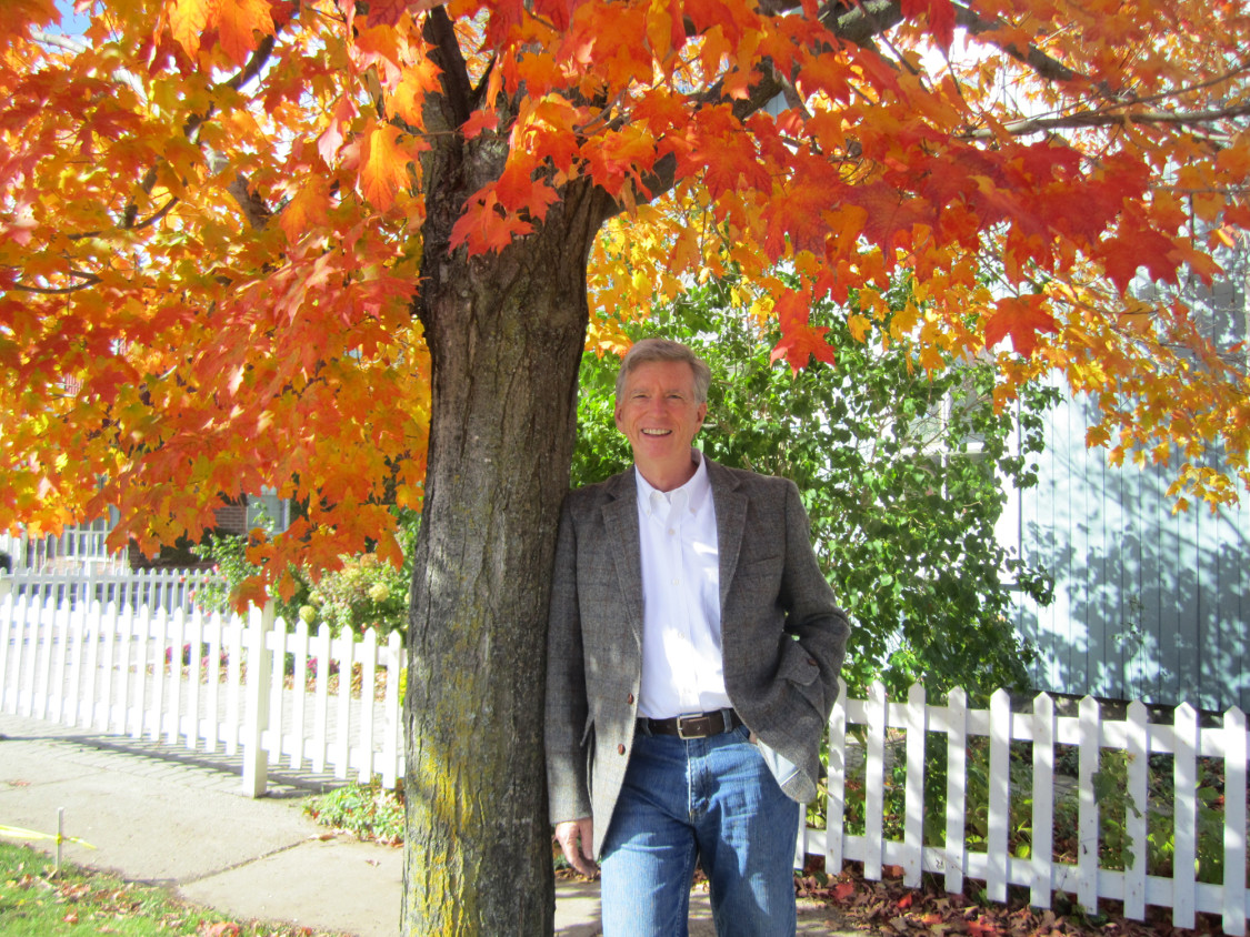 Marc Cullen standing beside a tree with orange leaves