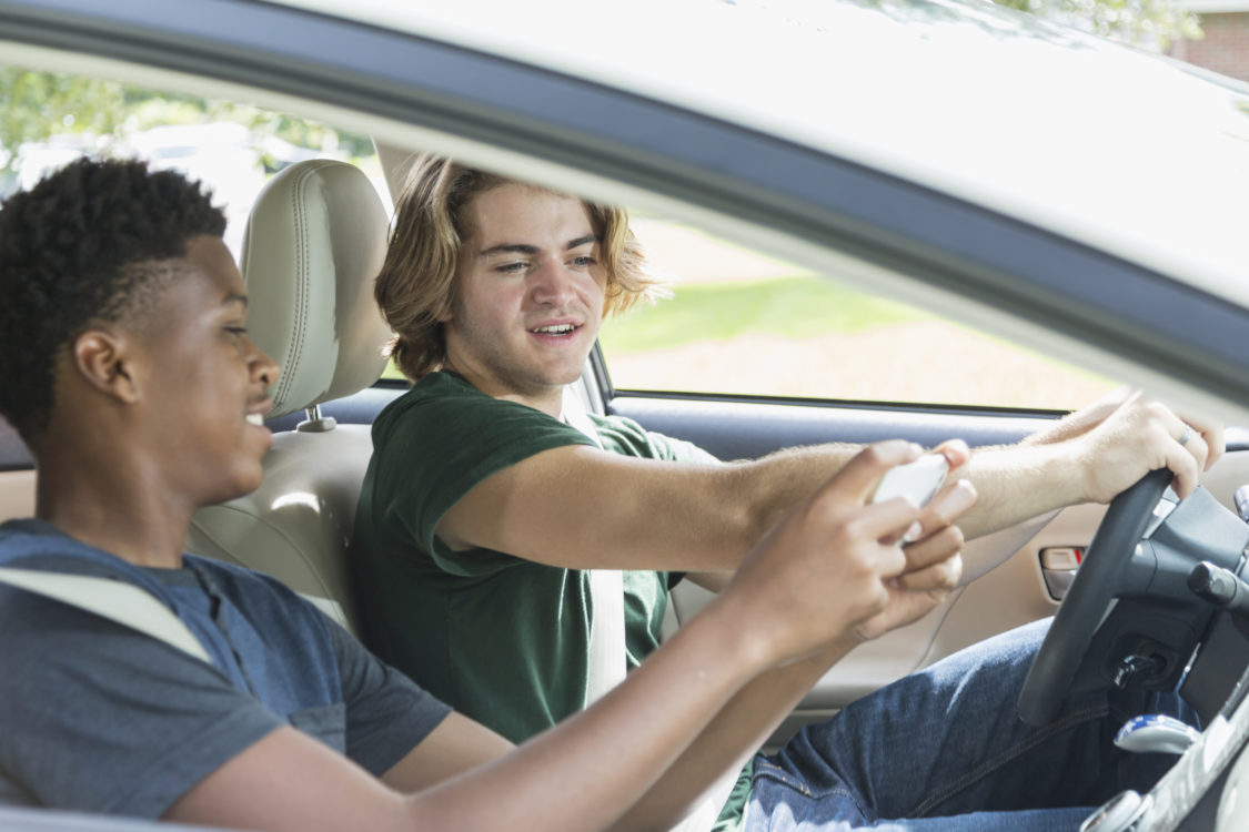 Teenage boys in car looking at mobile phone