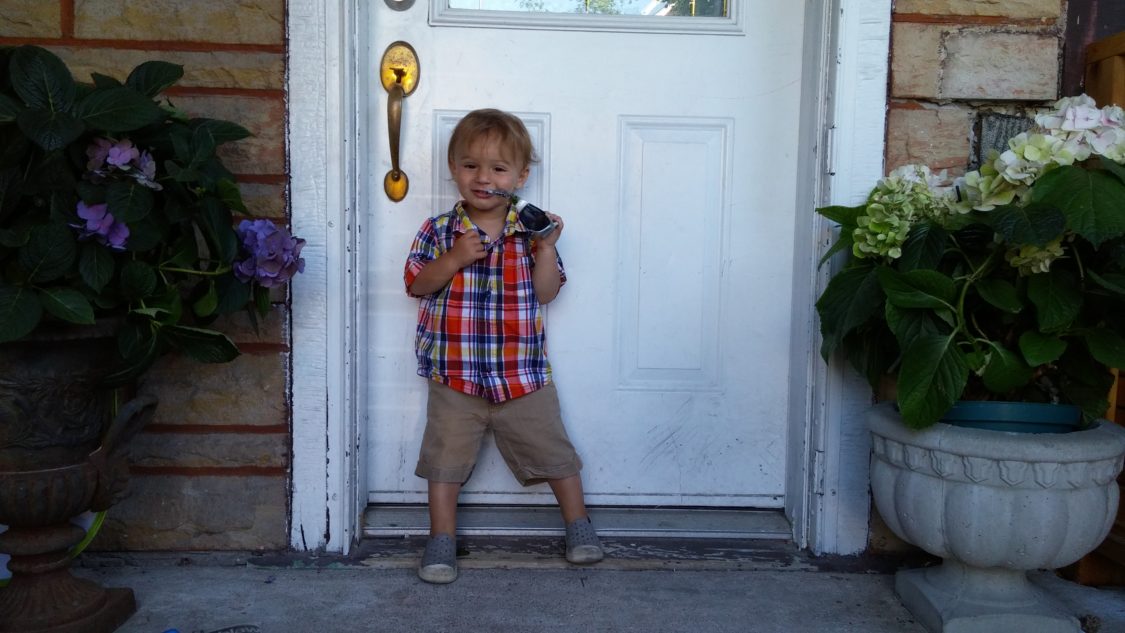 Image of the writer's son standing outside of the new house and holding a key.