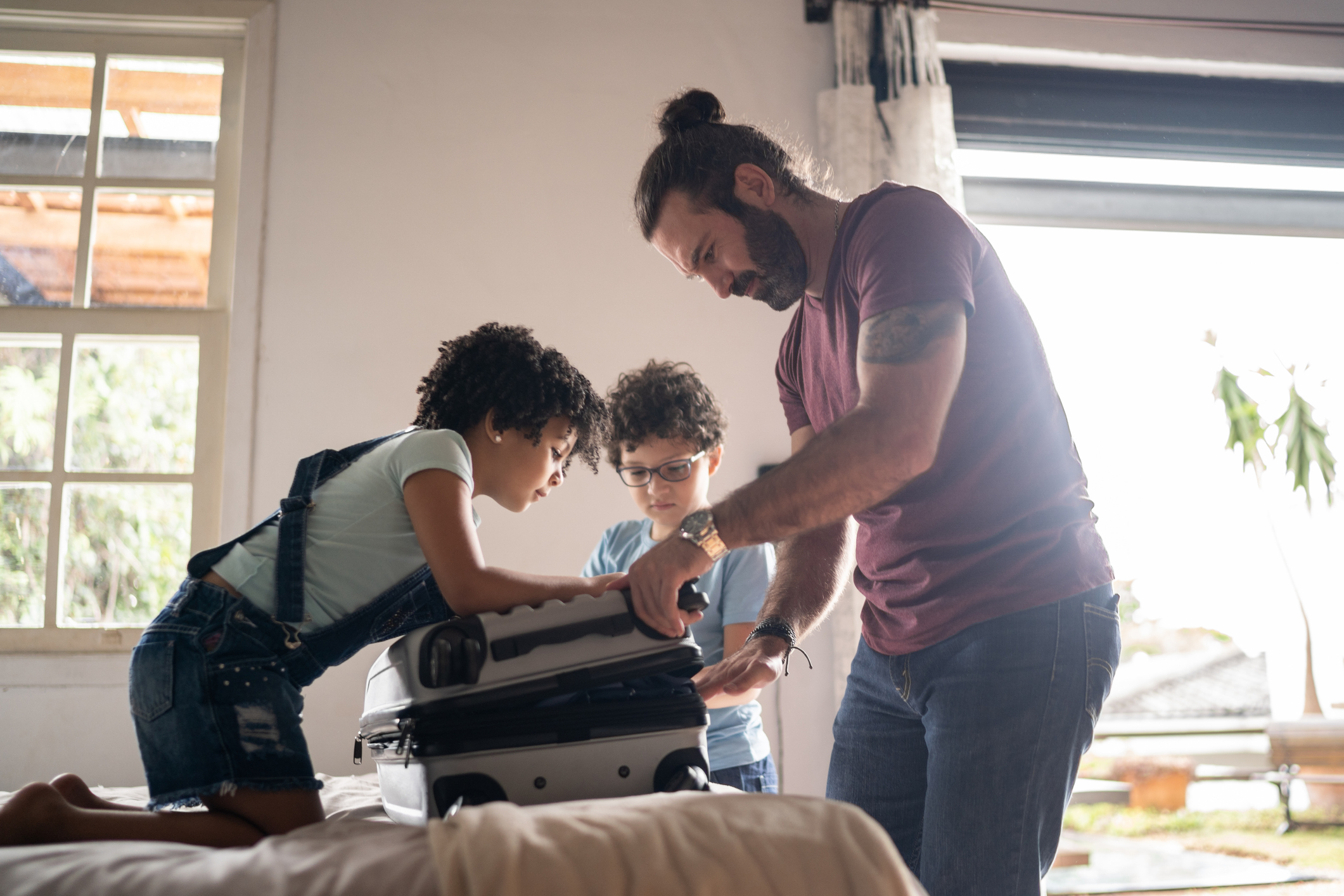Kids helping father packing his suitcase at home