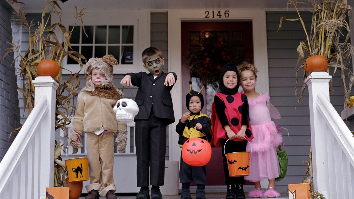 kids in costume standing in front of a house