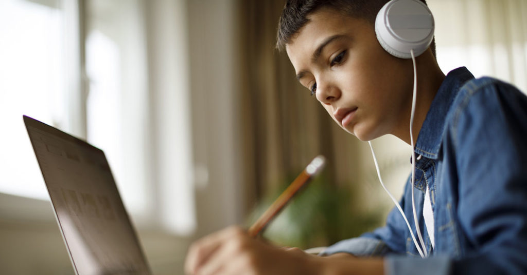 Un adolescent écoute de la musique tout en faisant ses devoirs.