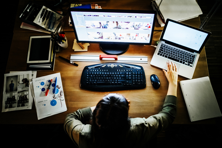 Jeune femme d'affaires travaillant avec un écran et un ordinateur portable dans un espace de bureau moderne.