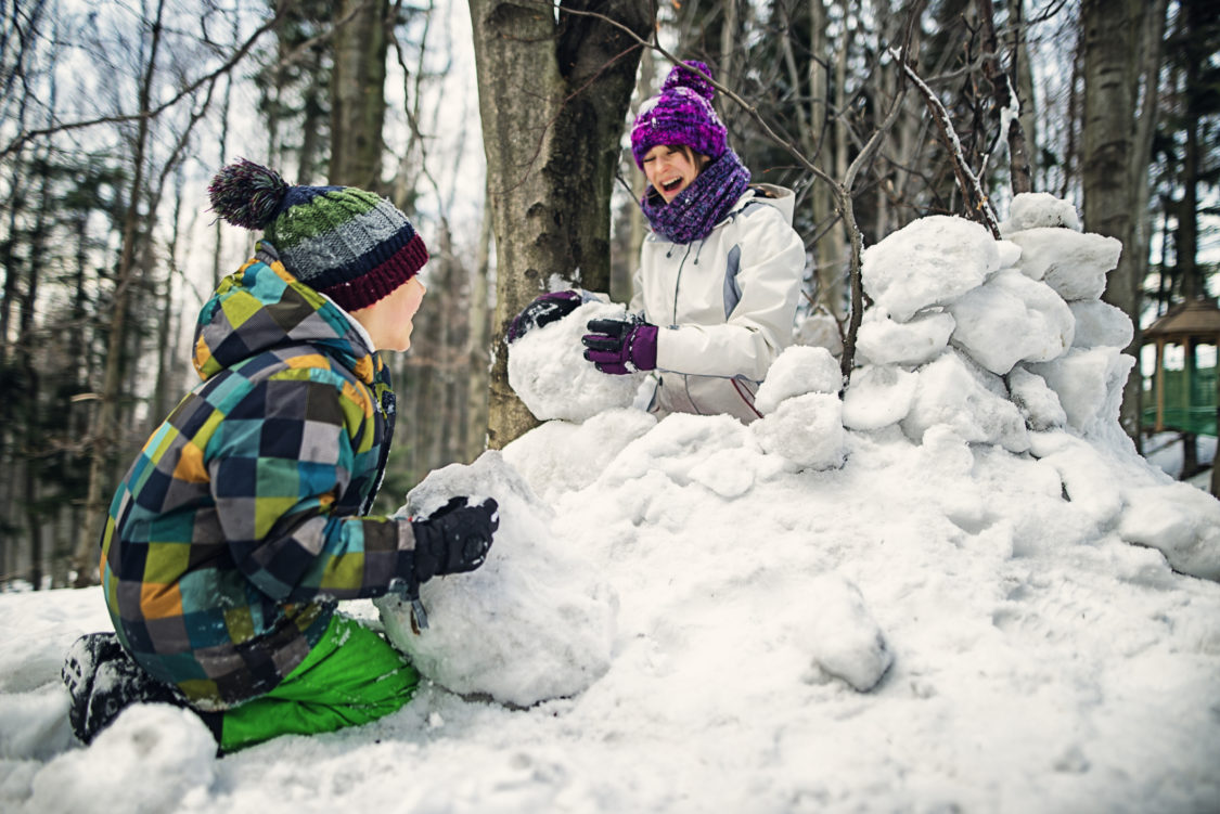 Frère et sœur profitant de l'hiver. Ils construisent une forteresse de neige. Les enfants sont âgés de 7 et 11 ans.