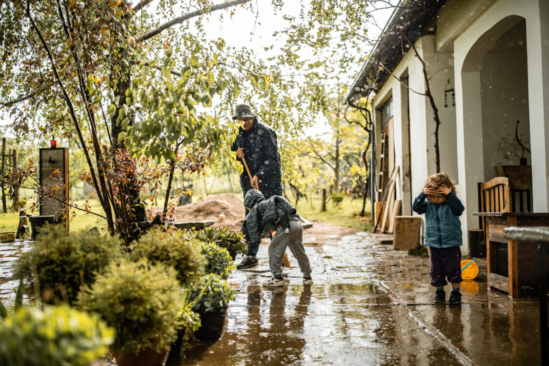 Fils aidant son père et balayant l'eau de la cour avant un jour de pluie