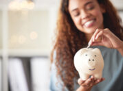 Woman pictured putting money into a piggy bank