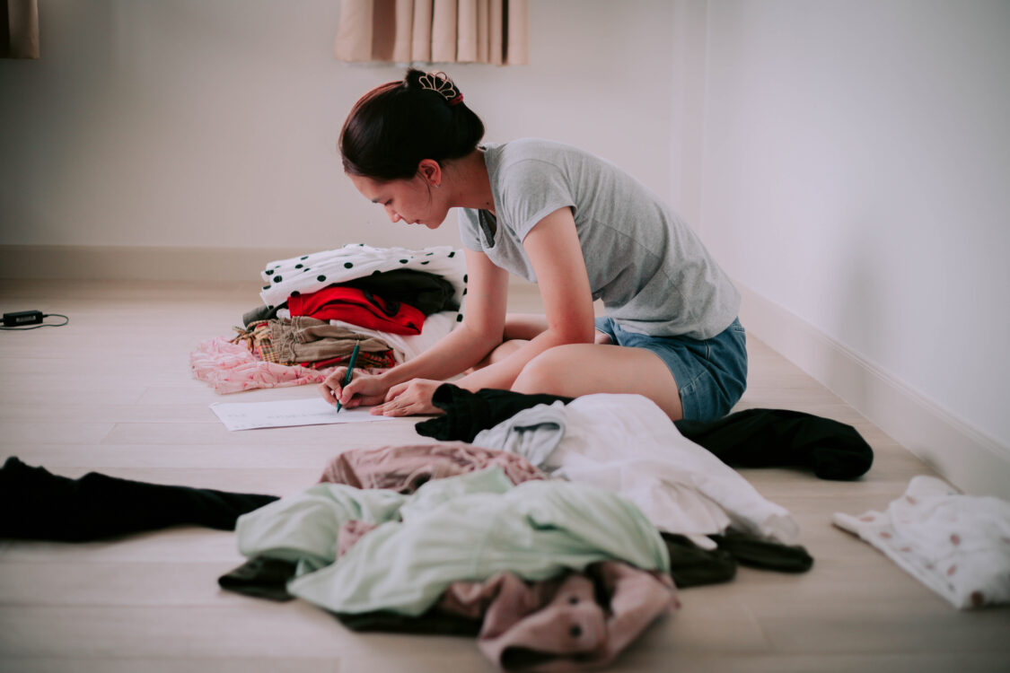Une femme passe en revue ses vêtements pour décider ce qu’elle doit garder ou ce dont elle doit se débarrasser afin de désencombrer sa chambre à coucher.