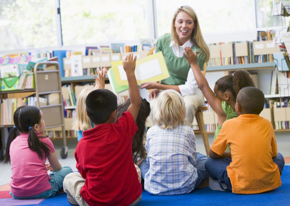 Professeur de maternelle lisant aux enfants dans la bibliothèque