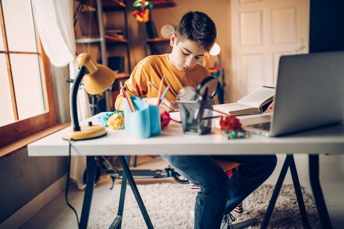 Young boy sitting in his room, doing homework