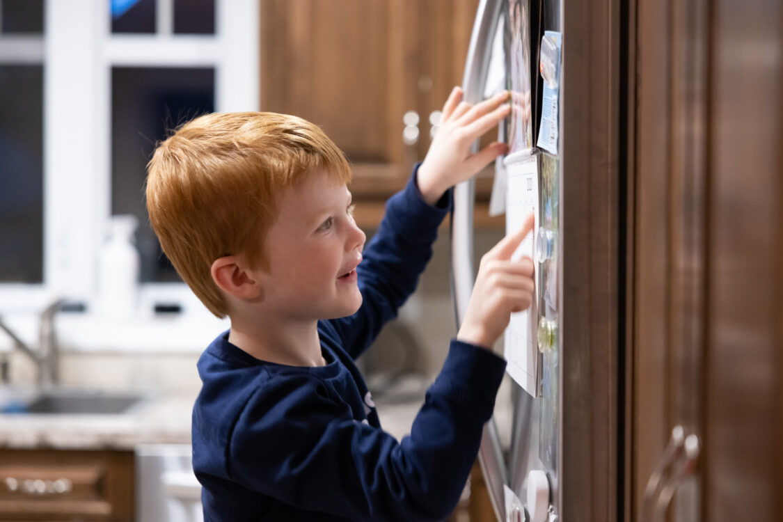 Child checking calendar on a refrigerator 