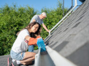 Senior Man And Woman Cleaning Their House Roof Gutters