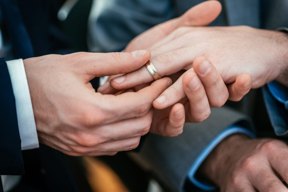 Gros plan sur la main d'un gay plaçant la bague sur la main de son ami lors de sa cérémonie de mariage gay